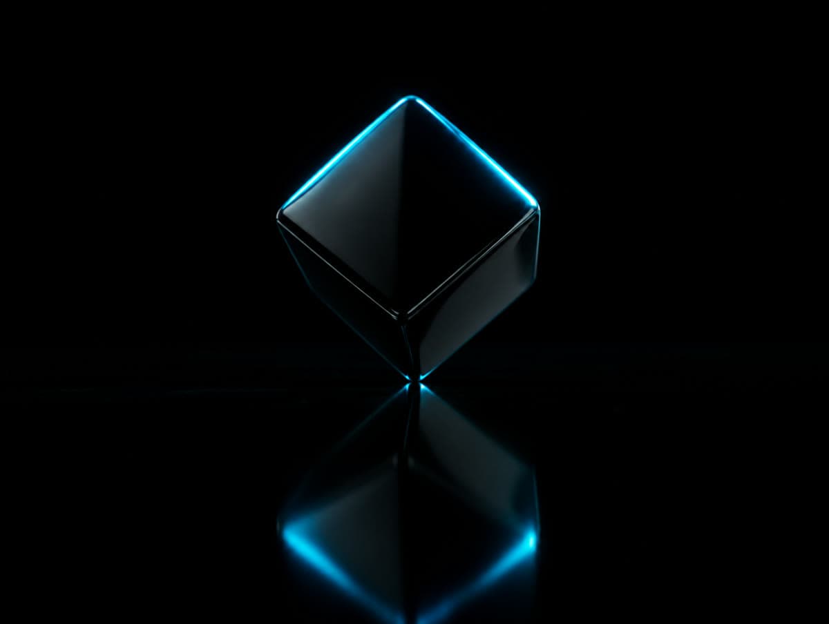 A black cube balanced on one corner on black glass
